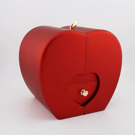 El Regalo especial - Rosa eterna y collar "A mi hija" es un joyero rojo en forma de corazón con detalles dorados y espacio para una rosa eterna -perfecto como regalo ideal para hija- que se muestra sobre un fondo blanco liso.