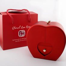 Cargar imagen en el visor de la galería, Un joyero rojo en forma de corazón con un pequeño cajón y un pomo dorado se encuentra junto a una bolsa de regalo a juego con la etiqueta &quot;Regalo especial - Rosa eterna y collar &#39;A mi hija&#39;&quot;, ideal para regalar a su hija algo realmente especial.