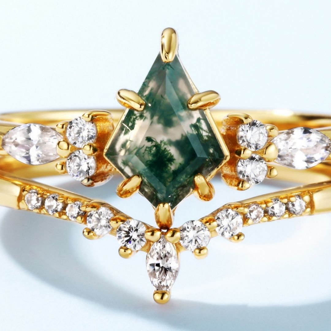 El Set de anillos piedra ágata verde presenta una piedra central en forma de cometa, similar al anillo de ágata musgosa, rodeada por brillantes piedras blancas marquesa y redondas en un diseño elegante y simétrico.