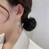 Una mujer con el pelo oscuro recogido en un moño bajo lleva una camisa blanca con cuello y el Set de aretes brillantes, con pendientes dorados en forma de media luna con cristales centelleantes. La foto destaca su oreja y las joyas sobre un fondo pálido.