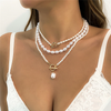 Una mujer que lleva un top de encaje blanco y el Collar de corazón de perla vintage® rezuma elegancia.